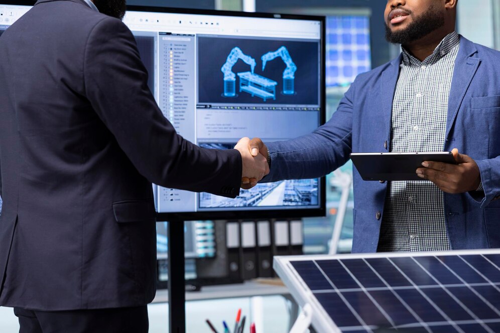 Two businessmen shake hands in front of a digital display showcasing robotic technology, with solar panels visible in the foreground.