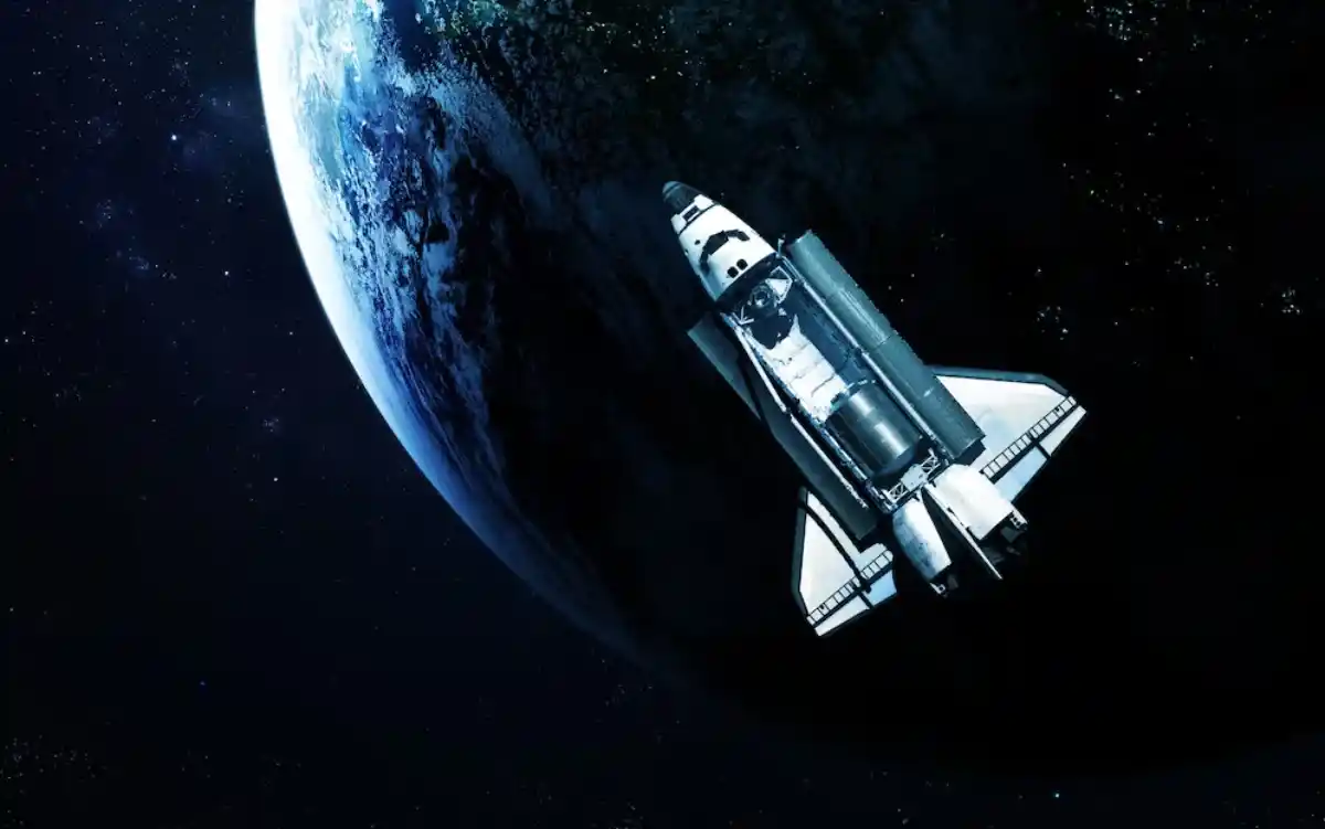 A space shuttle in orbit around a vividly detailed Earth against the backdrop of a star-filled dark blue sky.