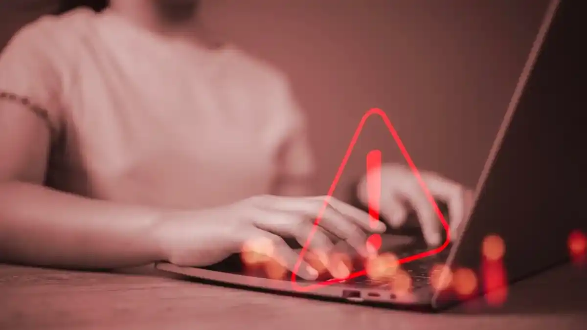 Person typing on laptop with warning